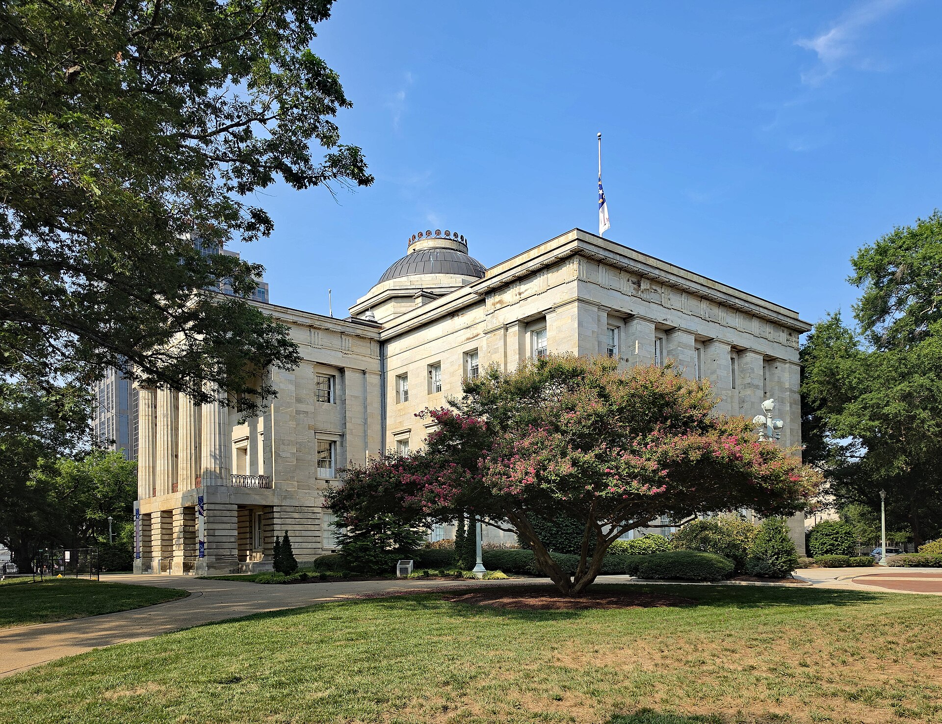 North Carolina State Capitol surrounded by trees and lawns in Raleigh.